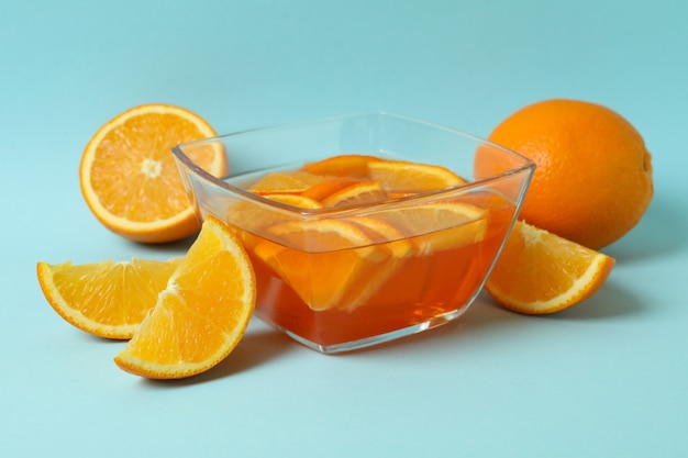 Bowl of orange jelly with orange slices on blue background