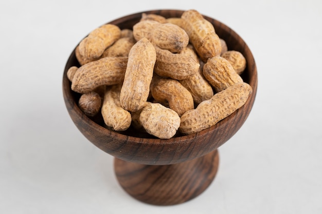 Bowl of organic peanuts in shell isolated on white surface