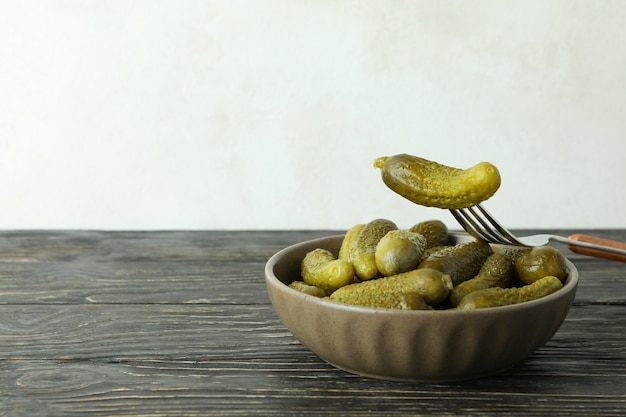 Bowl of pickles and fork on wooden table