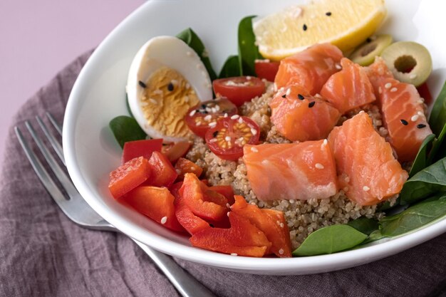 Bowl plate with poke dish fresh salmon quinoa spinach lemon for a healthy diet copy space