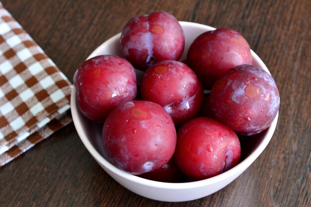 A bowl of plums on a table isolated closeup