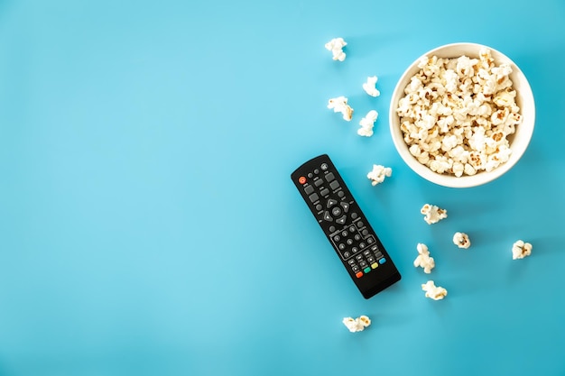 A bowl of popcorn a TV remote on a blue background