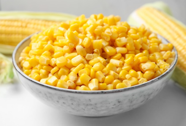 Bowl of preserved corn on white table closeup