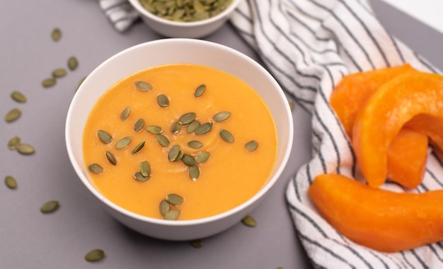 A bowl of pumpkin soup in a food composition on a grey background Healthy food vegan food