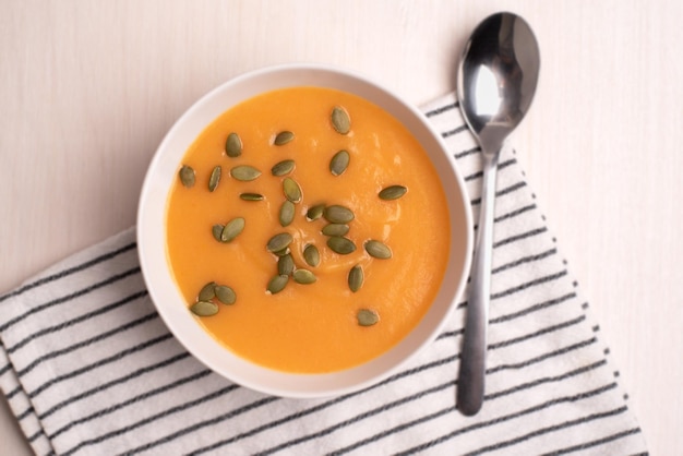 A bowl of pumpkin soup with a spoon on a light background Healthy food vegan food Top view flat