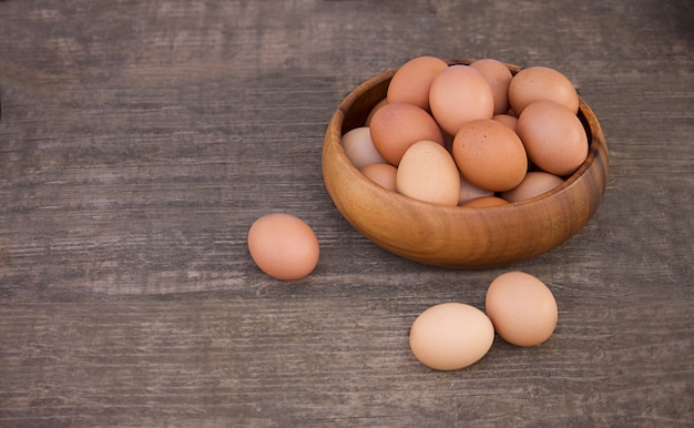 Bowl of raw fresh brown organic eggs on wooden background