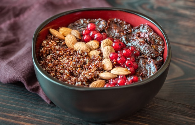 Bowl of red quinoa with olives, sun-dried tomatoes, berries and nuts