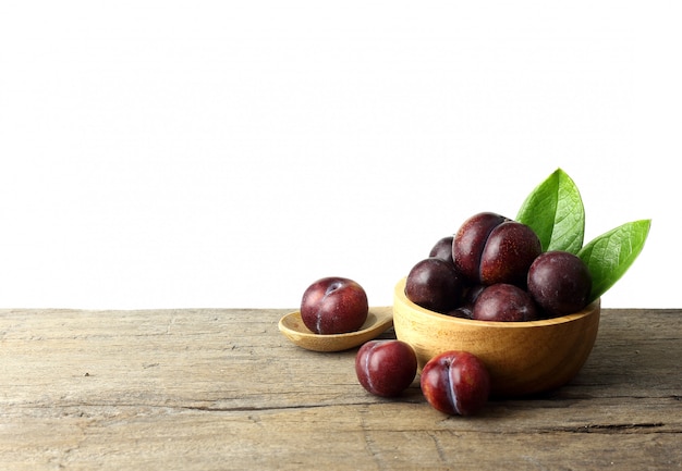 Bowl of ripe plums on wooden table