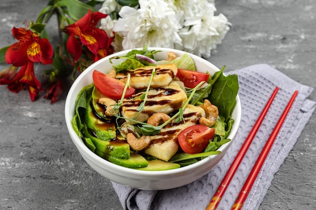 A bowl of salad with a bowl of tofu and vegetables.