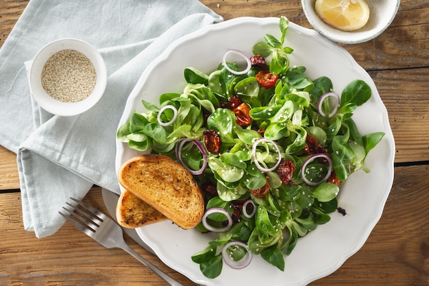 Bowl salad with mache leaves and baked tomatoes