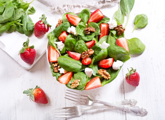 Bowl of salad with strawberry, spinach leaves and feta cheese, top view