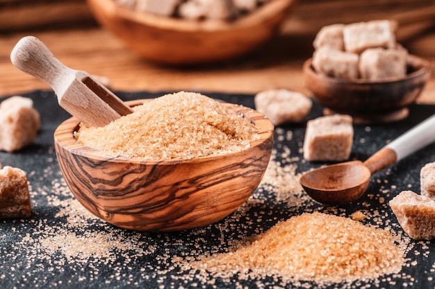 Bowl and scoop with sand and lump brown sugar on wooden background brown sugar cube Make unhealthy nutrition obesity diabetes dental care and much more