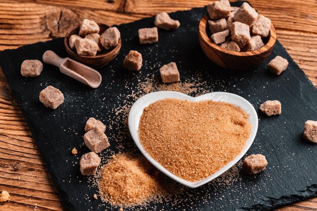 Bowl and scoop with sand and lump brown sugar on wooden background brown sugar cube Make unhealthy nutrition obesity diabetes dental care and much more