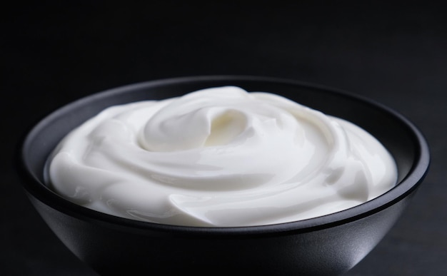 Bowl of sour cream on black background