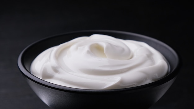 Bowl of sour cream on black surface