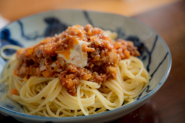 A bowl of spaghetti with meat sauce and cheese.