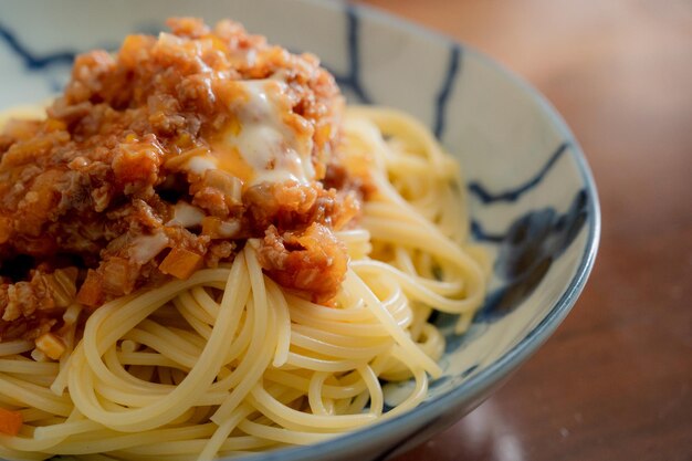 A bowl of spaghetti with a sauce and cheese on top.