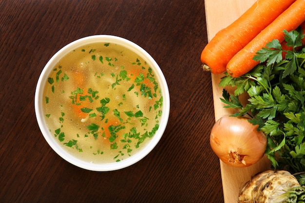 a bowl of traditional chicken soup served in a bowl over wooden