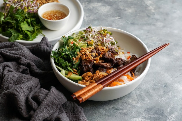 Bowl of traditional Vietnamese noodle salad - Bun Bo Nam Bo, with beef, rice noodles, fresh herbs, pickled vegetables and fish sauce