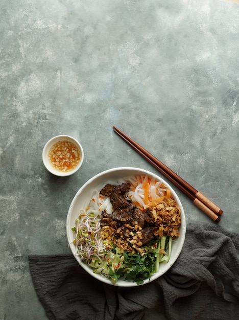 Bowl of traditional Vietnamese noodle salad - Bun Bo Nam Bo, with beef, rice noodles, fresh herbs, pickled vegetables and fish sauce