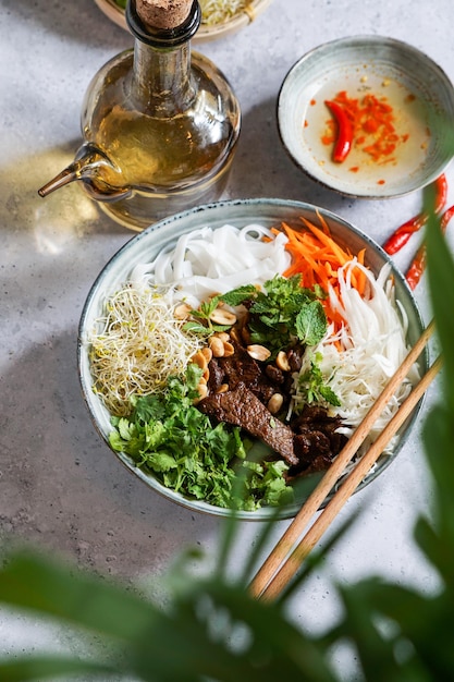 Bowl of traditional Vietnamese salad Bun Bo Nam Bo with beef rice noodles fresh herbs pickled vegetables and fish sauce