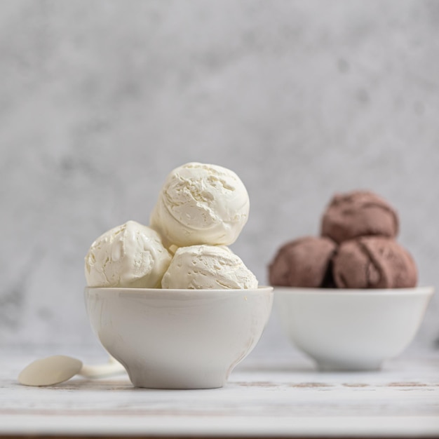 Bowl of vanilla and chocolate ice cream on light background Side view