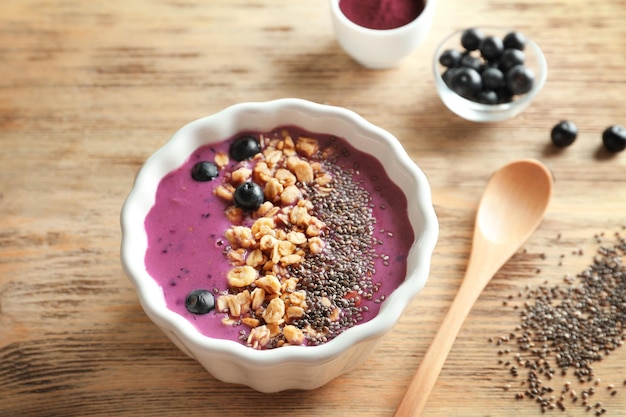 Bowl with acai smoothie muesli and chia seeds on wooden background