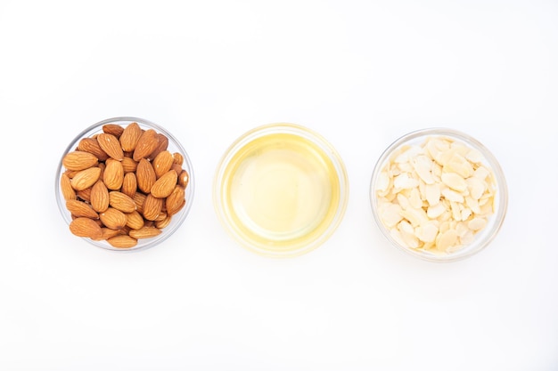 Bowl with almonds and almond oil and almond petals on white background