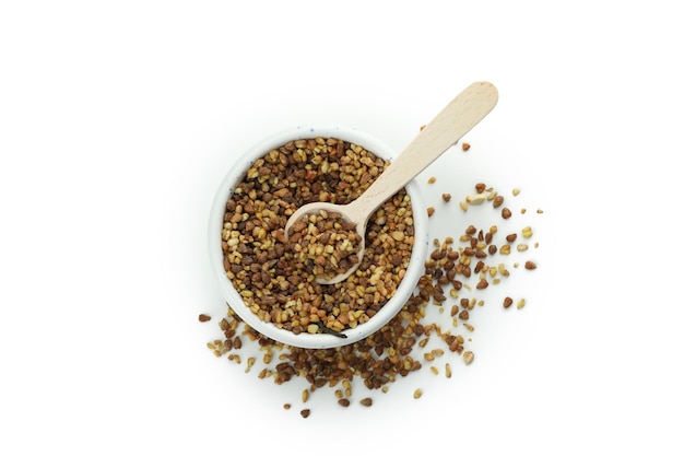 Bowl with buckwheat tea seeds and spoon isolated on white background