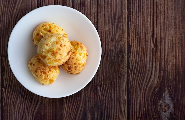 Bowl with cheese bread on wooden table