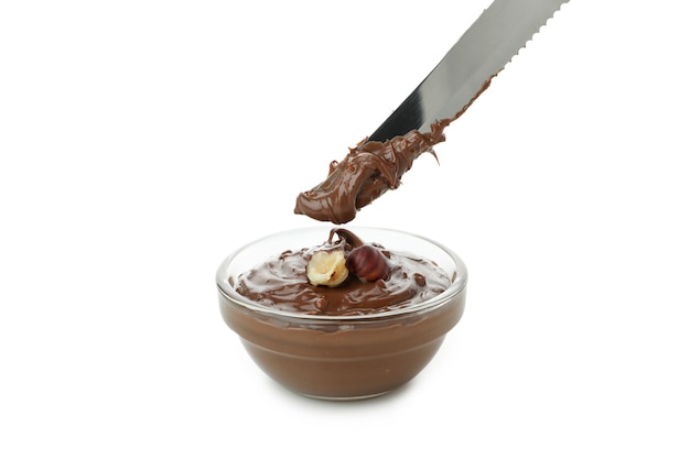 Bowl with chocolate paste and nuts, and knife isolated on white background