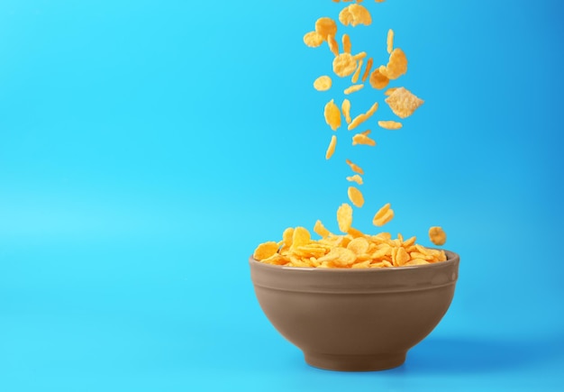 Bowl with corn flakes on blue background