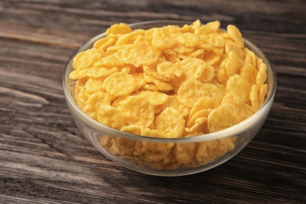 Bowl with cornflakes on wooden background