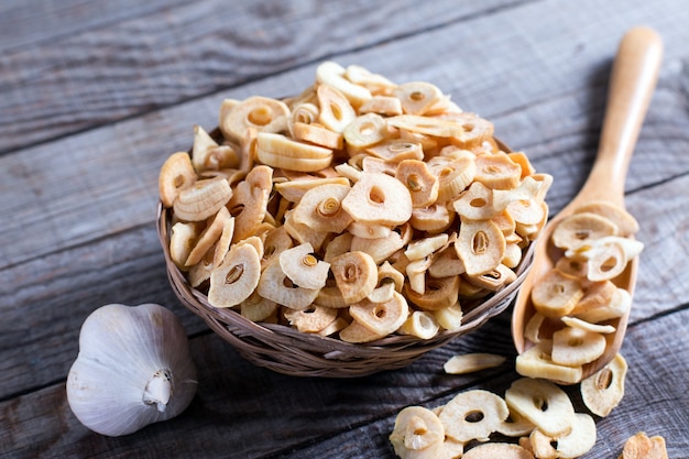 Bowl with dried garlic flakes on wooden background