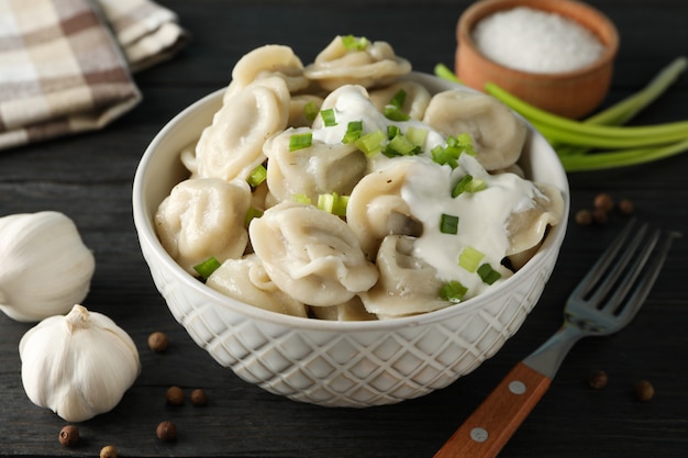 Bowl with dumplings and spices on wooden background, close up