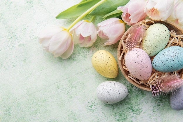 Bowl with Easter eggs painted pastel colors on a green wooden background