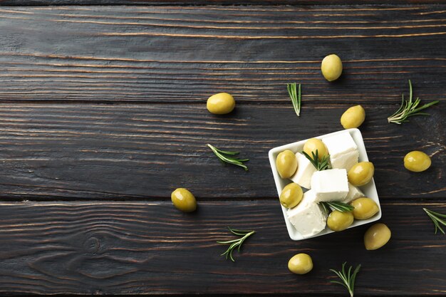 Photo bowl with feta cheese, olives and rosemary on wooden surface