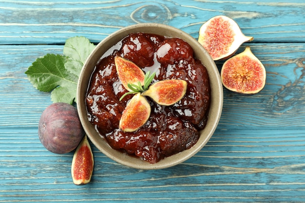 Bowl with fig jam and ingredients on wooden background