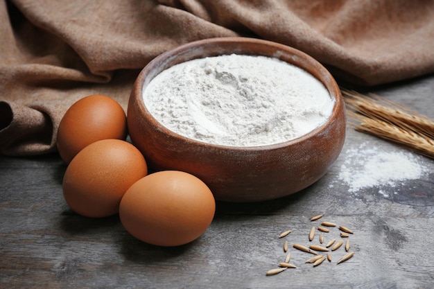 Bowl with flour and eggs on wooden table