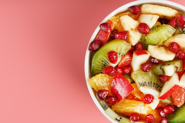 Bowl with fruit salad on pink