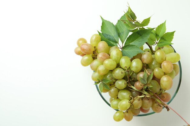 Bowl with green grape on white background, space for text