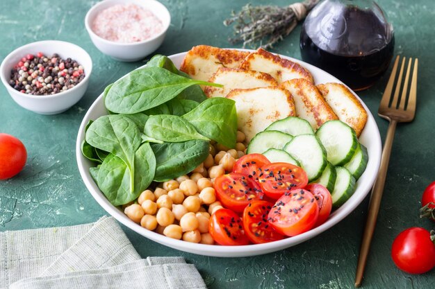 Bowl with grilled Halloumi cheese spinach chickpeas tomatoes and cucumbers Healthy eating Vegetarian food Diet