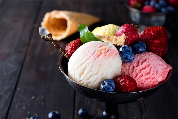 Bowl with ice cream with three different scoops of white, yellow, red colors and waffle cone