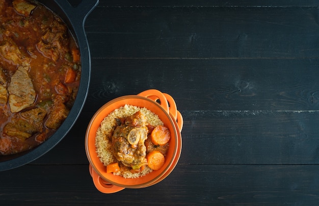 Bowl with Lamb with vegetables and couscous on black wooden background. Ramadan concept. Copy space. Top view.