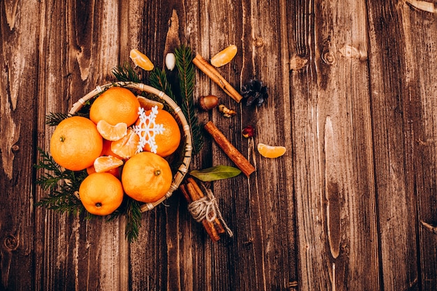 Bowl with little tangerines stands on the wooden table with species for Christmas drinks 