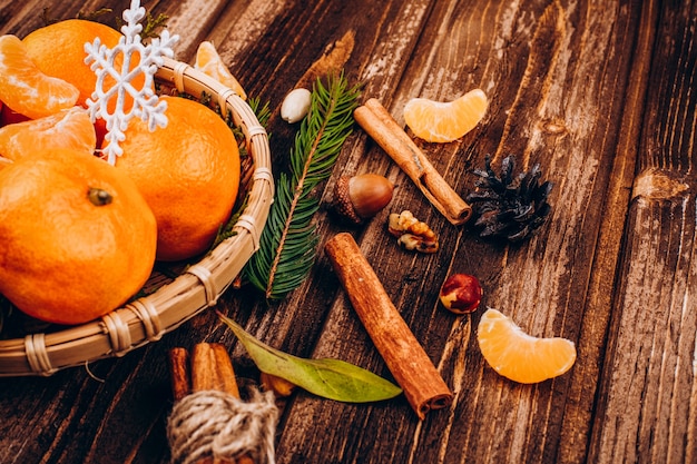 Bowl with little tangerines stands on the wooden table with species for Christmas drinks 