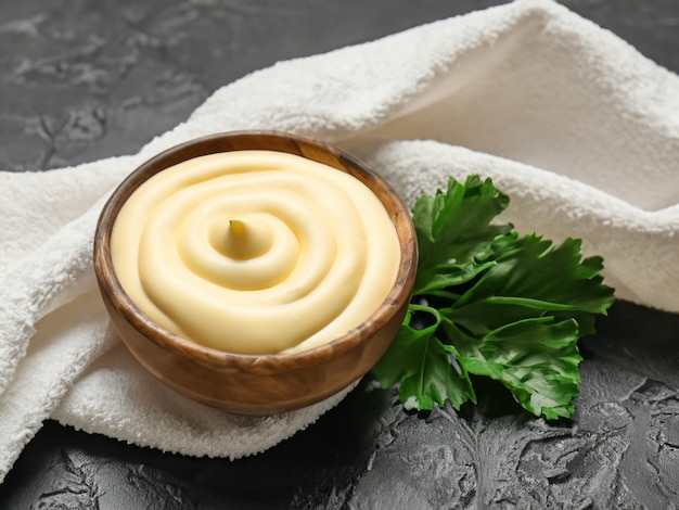 Bowl with mayonnaise parsley and towel on dark background