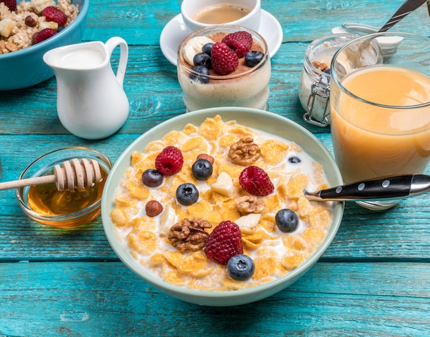 Bowl with oat flakes with raspberries and blueberries on a blue wooden table.