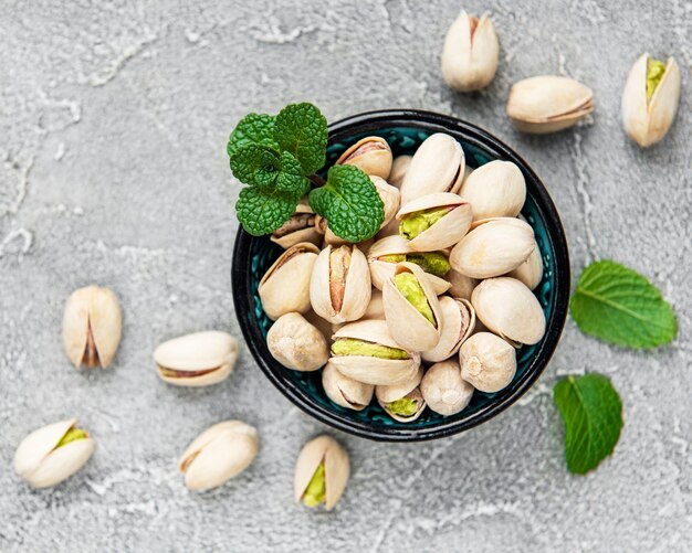 Bowl with pistachios on a grey concrete background