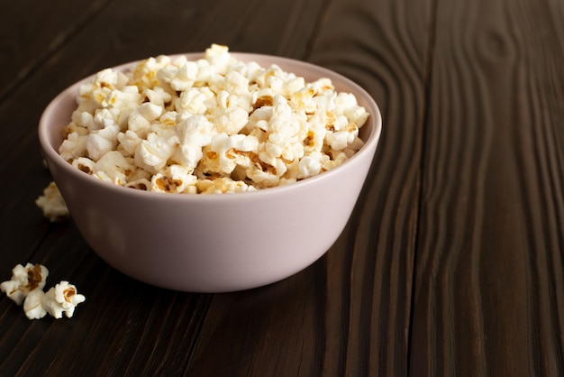 Bowl with popcorn on dark wooden table with copyspace